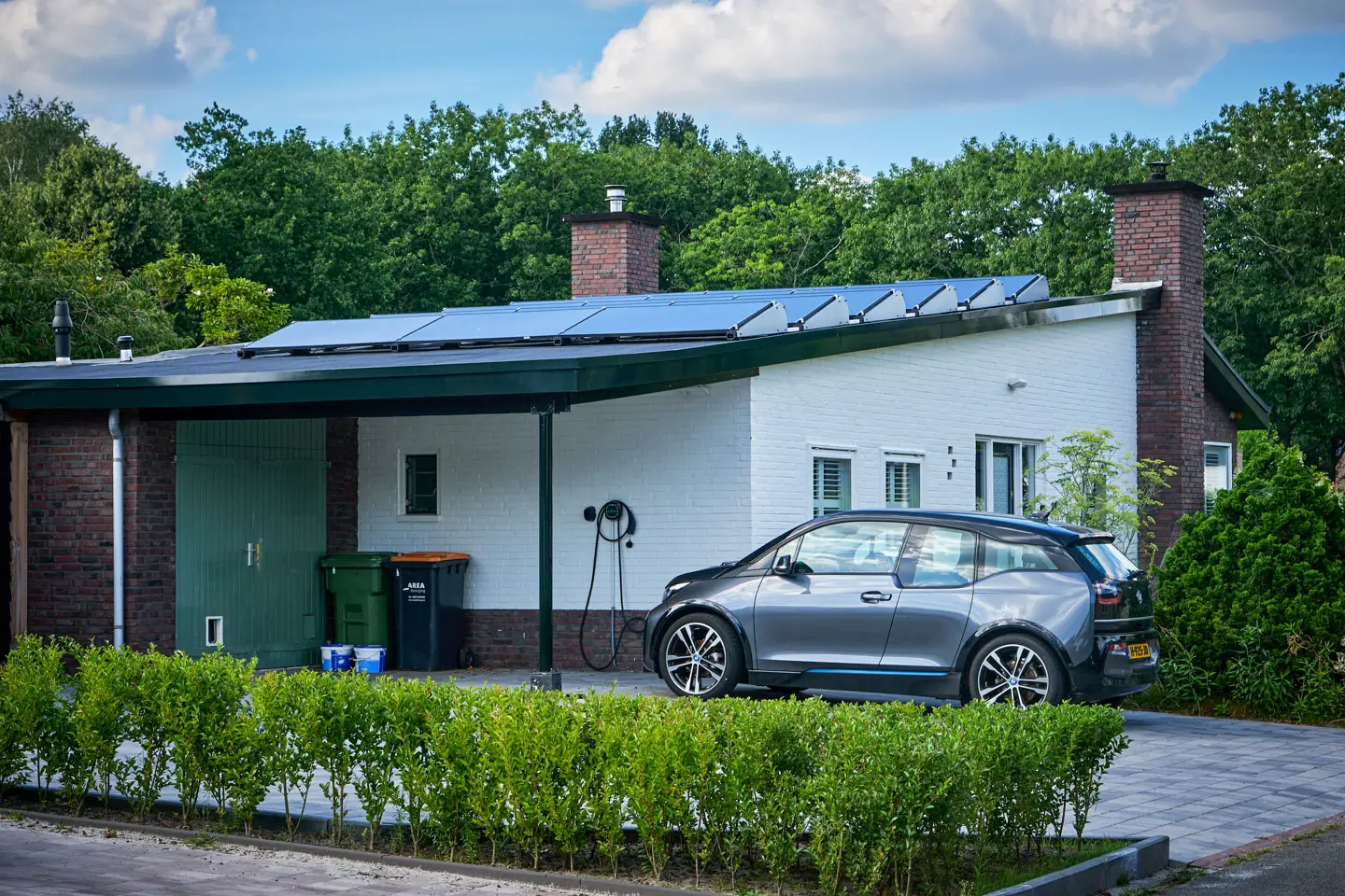 Einfamilienhaus mit Solaranlage auf dem Dach und Wallbox neben dem E-Auto