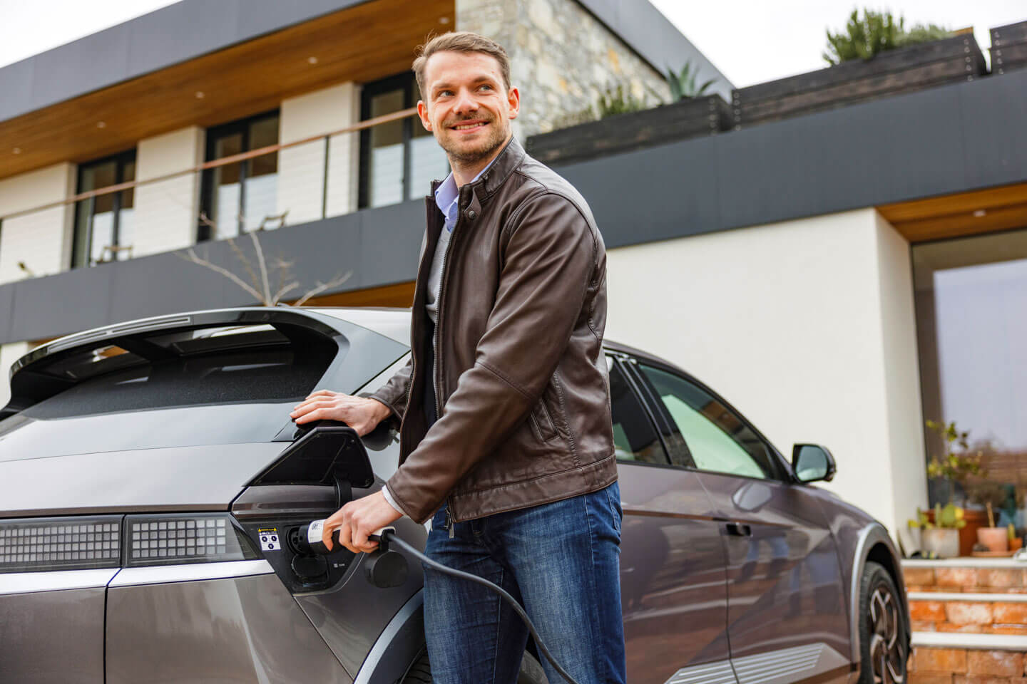 E-Auto lädt mit Solarstrom an der Wallbox vor einem Schweizer Einfamilienhaus