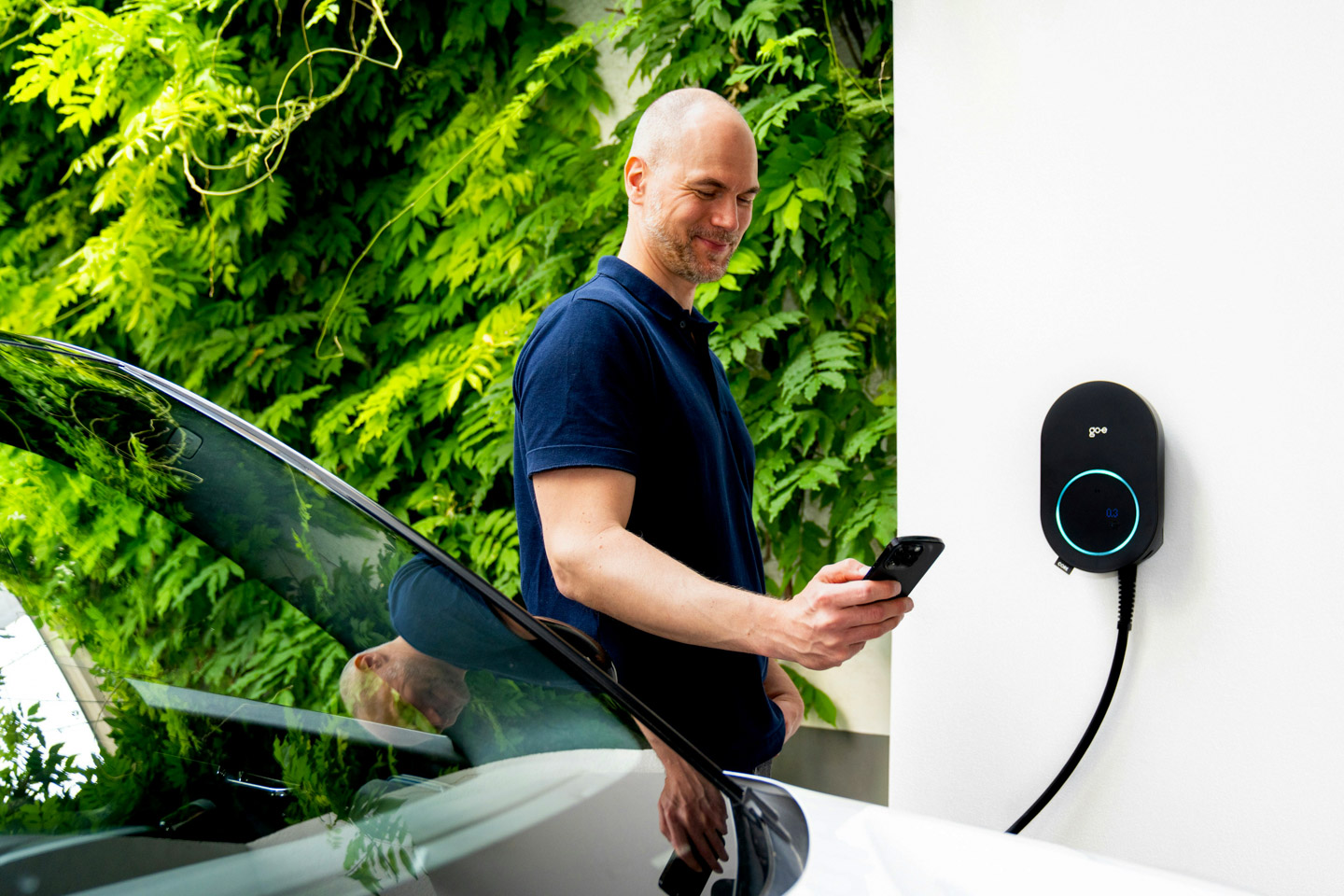 Familie kommt nach Hause, E-Auto lädt an der Wallbox in der Garage des Einfamilienhauses